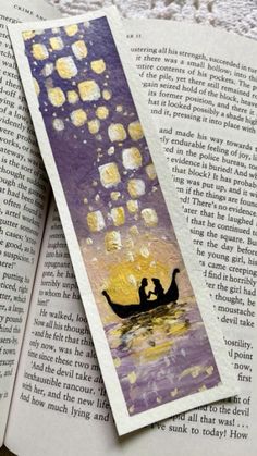 an open bookmark with two people in a boat floating on the water at night