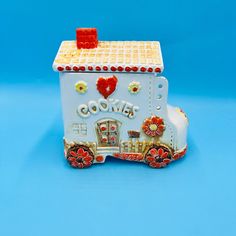 a cookie box shaped like a train with flowers and hearts on the front, sitting on a blue background