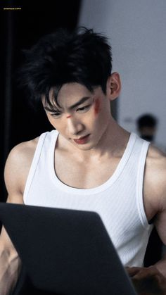 a man in white tank top using a laptop computer with blood on his face and chest