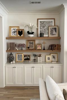 a living room filled with lots of furniture and pictures on the wall next to bookshelves