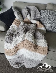 a crocheted blanket sitting on top of a couch next to a throw pillow