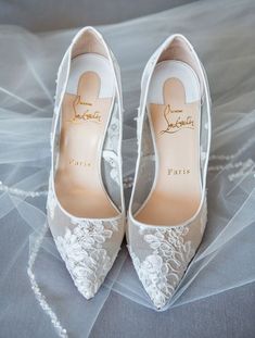 a pair of white wedding shoes sitting on top of a bed