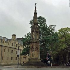 an old clock tower stands in the middle of a town square, surrounded by tall buildings