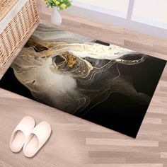 an area rug with a black and white painting on the floor next to slippers