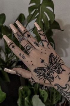 a person's hand with tattoos on it and a plant in the back ground