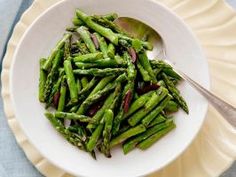 a white bowl filled with asparagus on top of a table