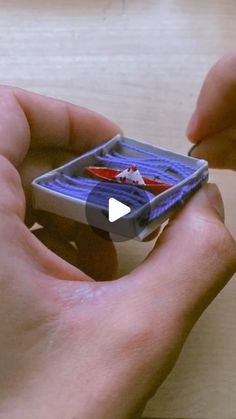 a person holding a small toy boat in their left hand and playing with it on the table