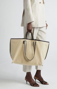 Contrast faux-leather trim highlights the East/West silhouette of this cotton-canvas tote that offers carrying versatility with top handles and shoulder straps. Snap-tab closure Top carry handles; shoulder straps Interior  pocket Textile/synthetic Made in Poland Designer Handbags Luxury Brown Shoulder Bag In Signature Coated Canvas, Cream Bags With Leather Trim For Work, Beige Workwear Bag With Canvas Lining, Cream Leather Trim Bag For Work, Cream Workwear Bags With Leather Trim, Luxury Everyday Cotton Canvas Bag, Luxury Cotton Canvas Bag For Everyday, Luxury Cotton Bags With Leather Trim, Luxury Cotton Canvas Bag With Leather Handles