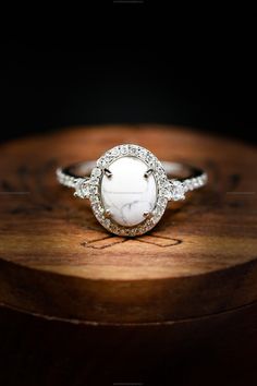 a close up of a ring on top of a piece of wood with diamonds around it