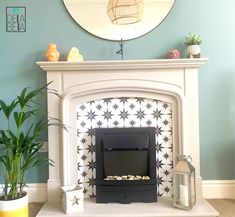 a living room with a fire place and potted plants on the fireplace mantel