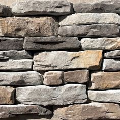 a stone wall made out of several different types of rocks, including gray and brown