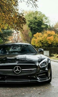 a black mercedes sports car parked on the side of the road in front of some trees