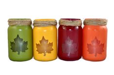 four mason jars with maple leaves painted on them