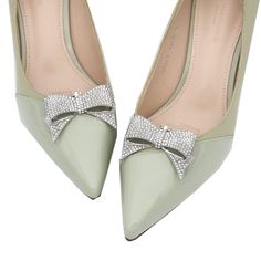 a pair of green high heels with bows on the toe and diamond embellishments