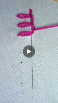 a video demonstrating how to make a hand stitched sign with pink yarn on white fabric