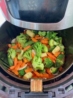 a bowl filled with broccoli and carrots next to an air fryer