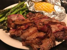 a plate with meat, asparagus and corn on the cob