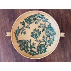 a green and white bowl sitting on top of a wooden table next to a brown floor