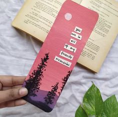 someone is holding up a bookmark with trees on it