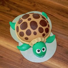 a cake shaped like a turtle sitting on top of a wooden table