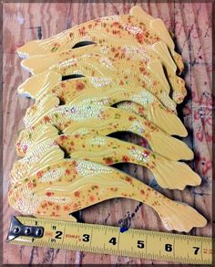 several yellow fish shaped objects sitting on top of a wooden table next to a ruler