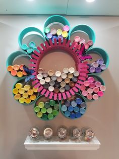 there is a colorful flower made out of crayons and paint tubes on the wall