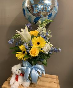 a bouquet of yellow flowers and white daisies in a vase with a teddy bear