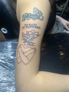 a woman with a tattoo on her arm that says no rain, no flowers and is holding a flower