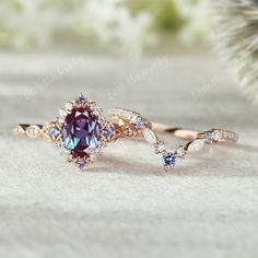 an engagement ring with a blue and purple stone in the center, on top of a white background