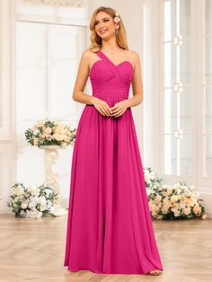 a woman in a bright pink dress standing on a wooden floor with flowers behind her