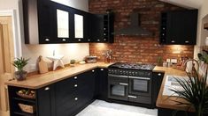 a kitchen with black cabinets and an oven in the center, surrounded by potted plants