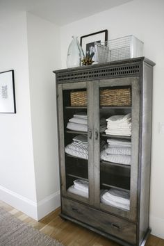 a cabinet with folded white towels on top of it in the corner of a room