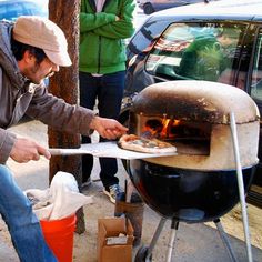 a man is cooking pizzas on an outdoor grill