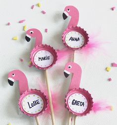 three pink flamingos are sitting on top of some cupcakes with name tags