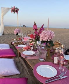 the table is set with pink flowers and place settings