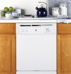 a white dishwasher sitting on top of a kitchen counter next to wooden cabinets