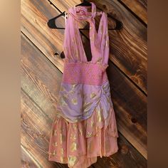 a pink and gold dress hanging on a wooden wall