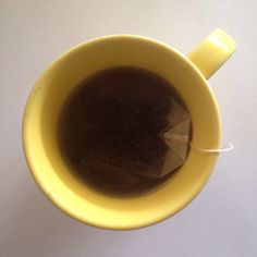 a yellow cup filled with liquid on top of a white table