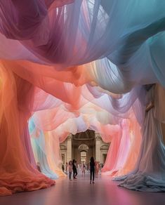 people are walking through an art installation with colorful fabric covering it