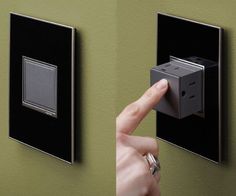 a person pressing the switch button on a green wall with two black and silver switches