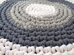 a circular rug made out of yarn on top of a carpeted floor with white and gray circles