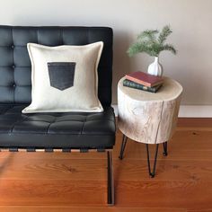 a black chair with a white pillow on it next to a small table and books