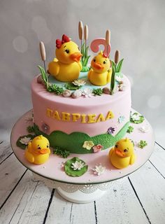 a pink cake with two rubber ducks on it