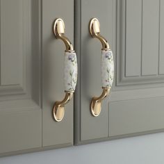 two gold handles with flowers on them in front of gray cupboards and white cabinets