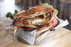 a bucket full of crabs sitting on top of a wooden table