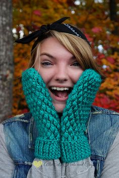 a woman wearing a green knitted mitt with a black bow on her head