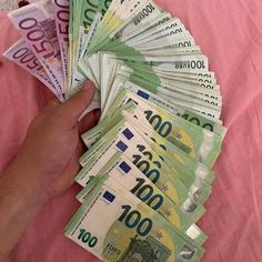 a person holding money in their hand on top of a pink cloth covered tablecloth