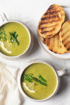 three bowls of soup with grilled bread and asparagus on the side next to each other