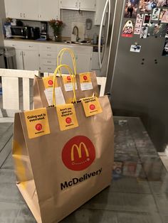 a brown paper bag with mcdonald's stickers on it sitting in front of a refrigerator