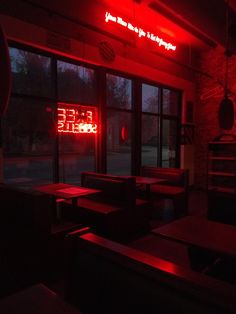 an empty restaurant with red neon signs on the wall and tables in front of it